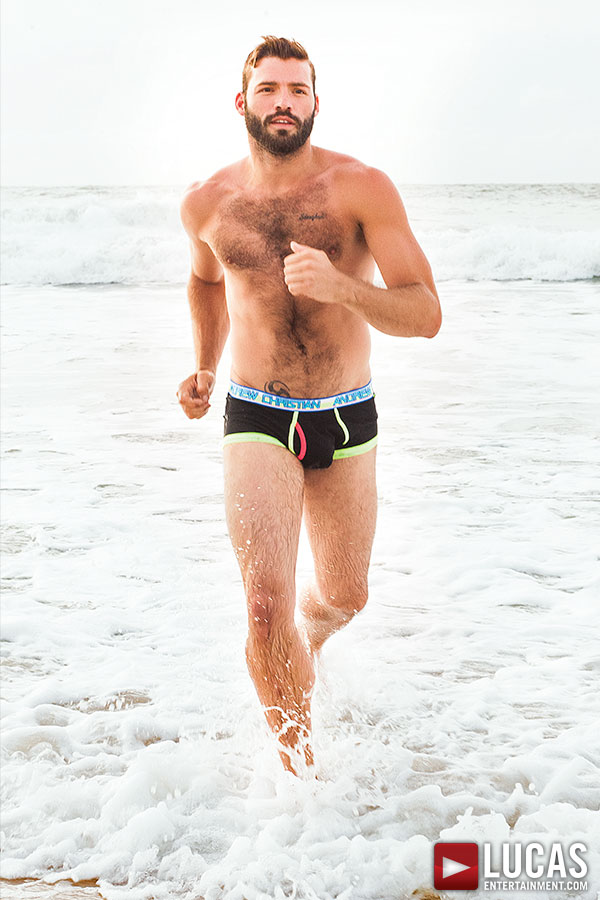 Xavier Jacobs, gay porn otter, runs on the beach.